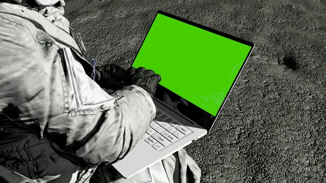 科幻的场景。未来的月球殖民地。宇航员在月球上用绿色屏幕的笔记本电脑打字。视频素材