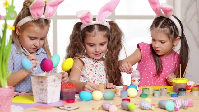 快乐的小朋友戴着兔子耳朵画复活节彩蛋。视频素材