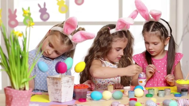 快乐的小朋友戴着兔子耳朵画复活节彩蛋。视频素材