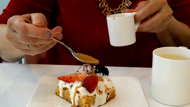 女人把糖浆倒在白色的杯状蛋糕上。视频素材