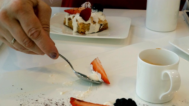 女人吃蛋糕装饰的浆果，用茶匙。视频素材