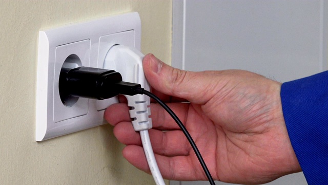在墙上的插座上，手插电线靠近手机充电器视频下载