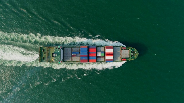 航拍俯视图集装箱船以美丽的波浪图案全速行驶在海上，用于物流、航运、进出口或运输。视频素材