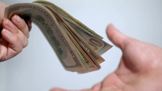 一个女人的手拿着白底上的美元。特写镜头视频素材
