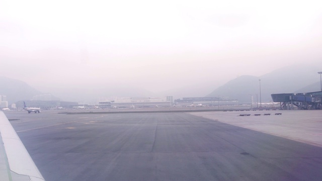 在机场航站楼起飞跑道上驾驶时从飞机窗口看到的景象。从现代机场窗口可以看到降落后在跑道上移动的飞机视频素材
