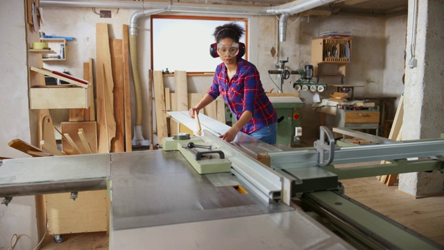 一个年轻的女人正在桌子上锯一块木板视频素材