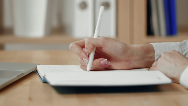 商务女性的手写就是用笔在记事本上写字，用笔记本电脑。视频下载