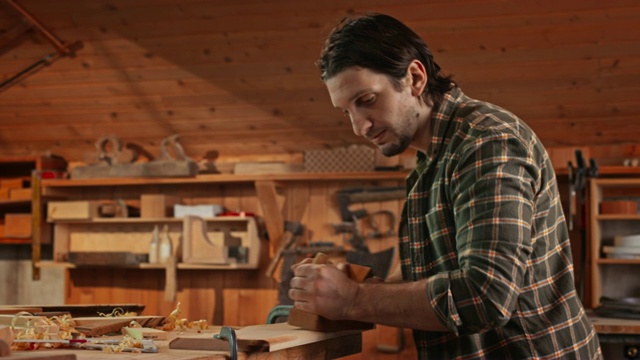 男木匠，在他的车间里用千斤顶刨子刨木板视频素材