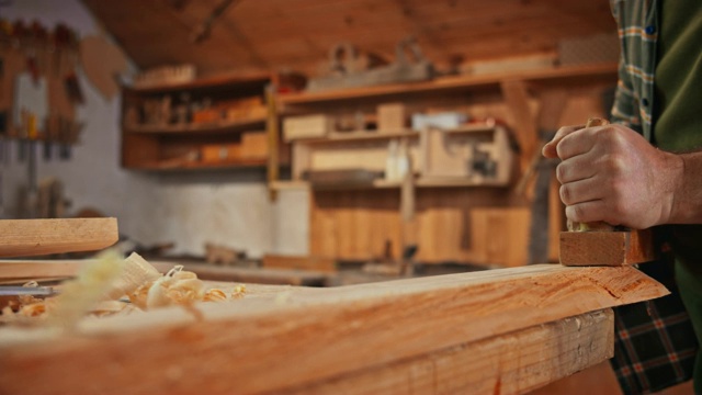 一位男性木匠的手正在用一架飞机来塑造一块木头视频素材