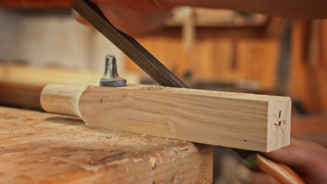 一名男子的手用锉刀来塑造一块木头，用钳条夹住视频素材