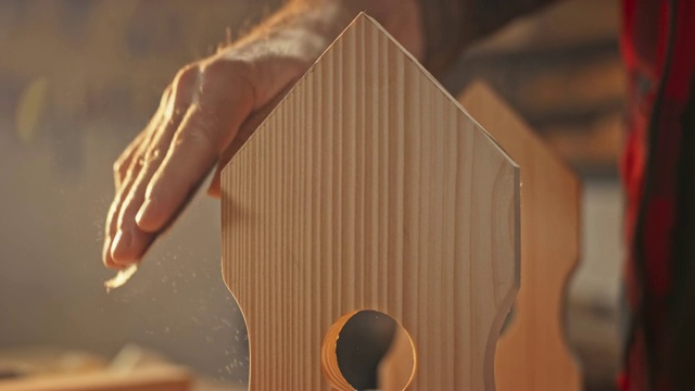 一个人用砂纸完成一个鸟屋的表面视频素材