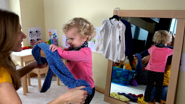 女人把她小女儿的围巾放在镜子前视频素材
