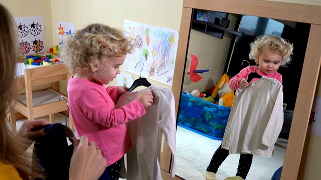 妈妈和她的小女儿在镜子前量衣服视频素材