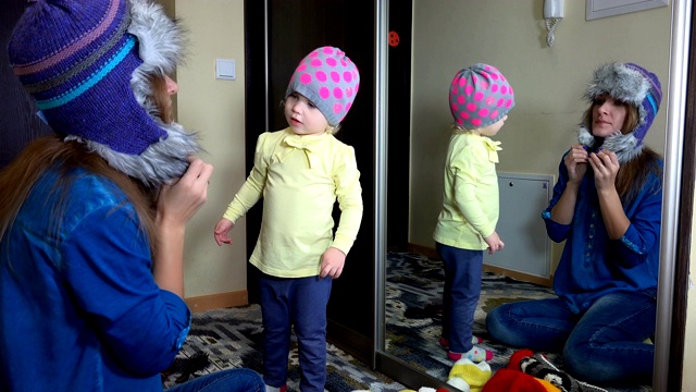 女人与女孩测量温暖的冬天帽子近镜视频素材