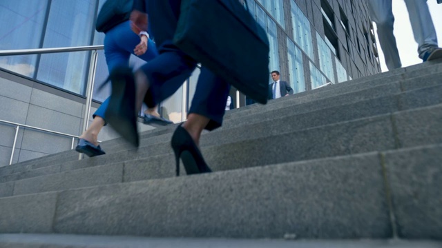 一个穿着高跟鞋的女商人的腿在一幢现代商业大楼前的楼梯上视频素材