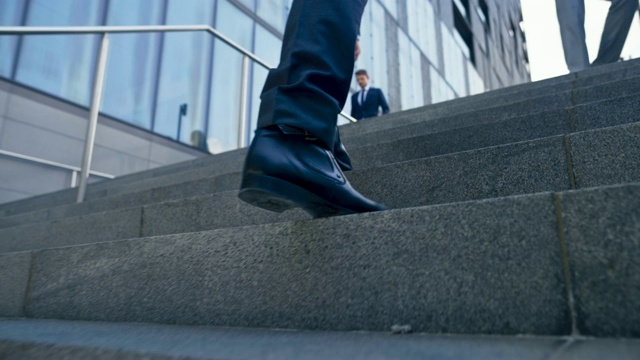 SLO MO TS一个商人的腿，穿着黑色的鞋子和西装正走在商业大厦外的楼梯上视频素材