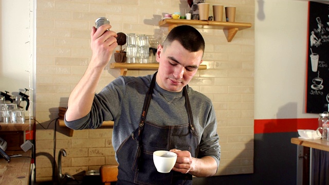 在一家现代咖啡店里，咖啡师倒进一杯咖啡肉桂。视频下载