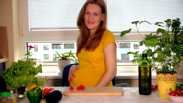 快乐的怀孕的妻子女人吃红莓，看着镜头微笑的脸视频素材