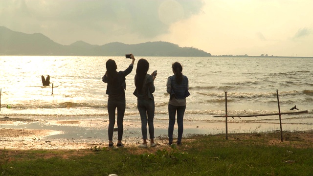 一群年轻女子跑去拍美丽的日落美景在水边视频素材