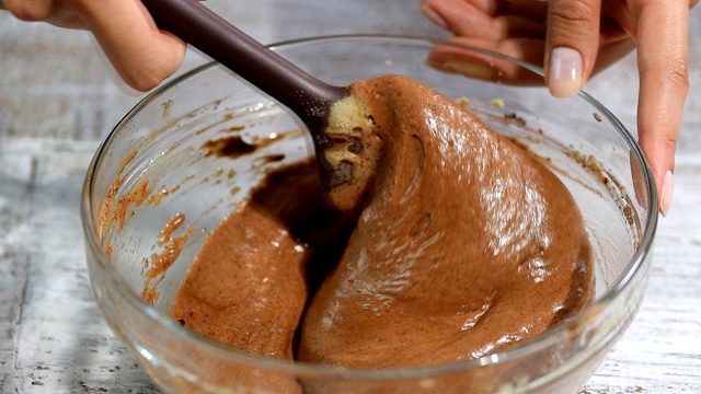 女用铲子用手搅拌巧克力面糊。视频素材