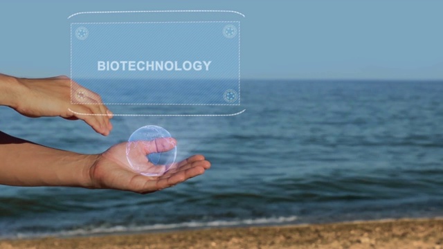 男性的手在海滩上拿着一个概念全息图与文字生物技术视频下载