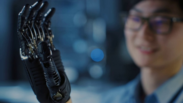 一个未来的假体机器人手臂被一个专业开发工程师在一个高科技研究实验室与现代计算机设备测试的近距离。视频素材