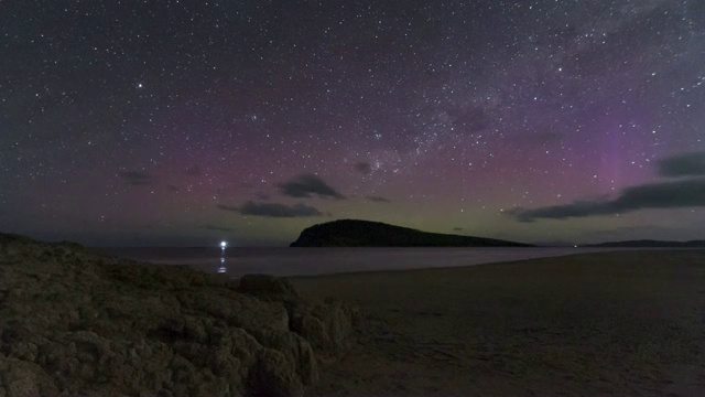 在塔斯马尼亚岛的海滩上，一个孤独的身影在看着南极光的时间流逝。视频素材