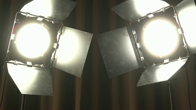 剧场演播室的聚光灯在棕色窗帘上。生产胶片的照明同时开启和关闭视频素材