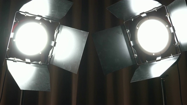 剧场演播室的聚光灯在棕色窗帘上。制作胶片的灯光一次打开和关闭一个视频素材
