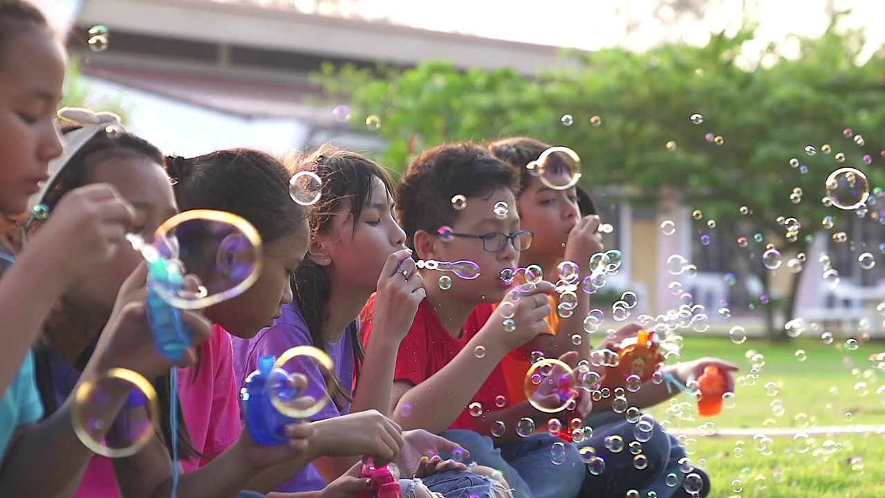 一个亚洲孩子在夏天的田野上玩肥皂泡。快乐的童年的概念。真实的生活画面。视频下载
