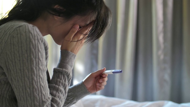 可悲的亚洲妇女正在用验孕棒怀孕视频素材