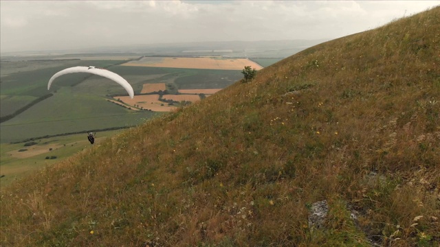 专业滑翔伞降落在山坡上的鸟瞰图。Paraglide运动视频素材