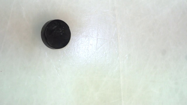 冰球旋转并以慢镜头落在冰面上木棍击中冰面，俯视图视频素材