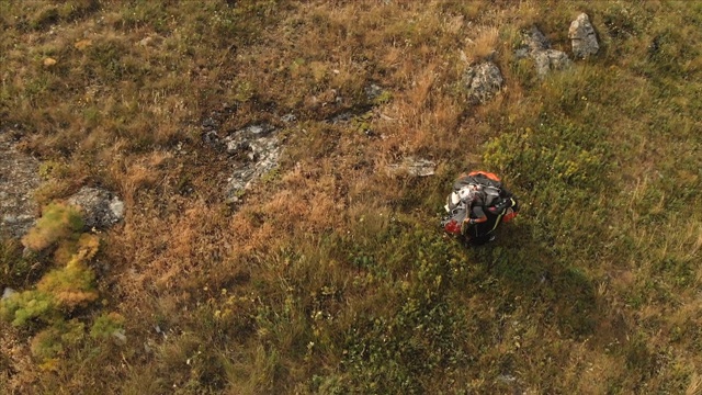 专业滑翔伞降落后的鸟瞰图，将滑翔伞放在肩膀上，从山坡上走下来，到达发射地点。Paraglide运动视频素材