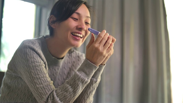 快乐的亚洲妇女感到快乐后，检查怀孕测试的阳性结果视频素材