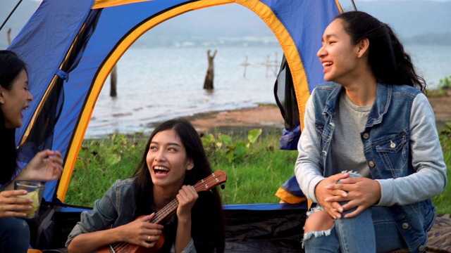 特写手持式正面视图:三个女人花周末时间露营在日落的水边视频素材