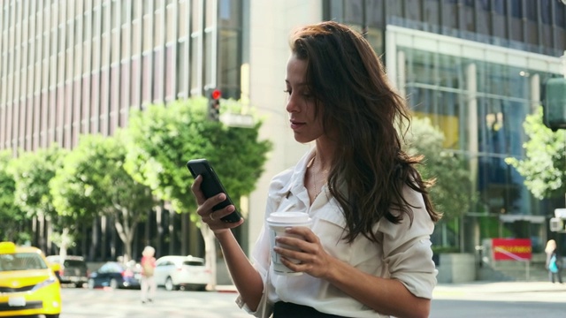 年轻的商业女性使用智能手机和喝咖啡在路上视频素材