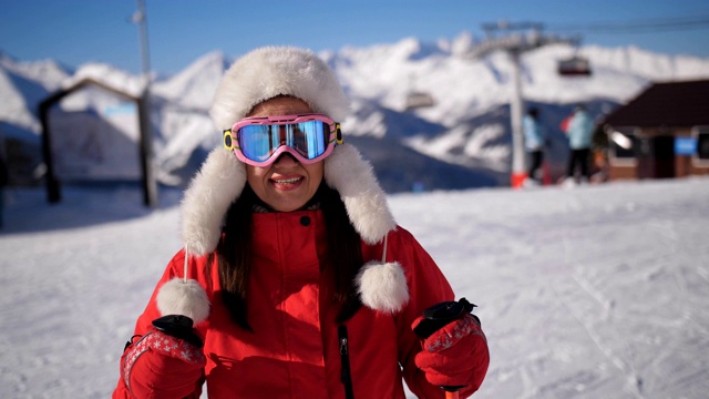 一个滑雪胜地的女人走到摄像机前，摘下了滑雪镜。视频下载