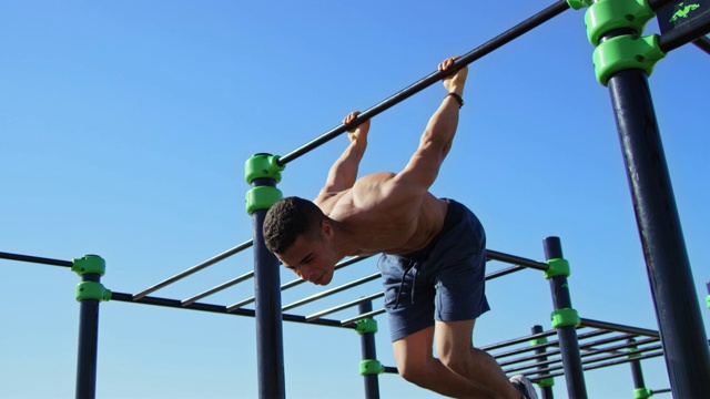 男运动员在海滩上挂在体操杆上视频下载