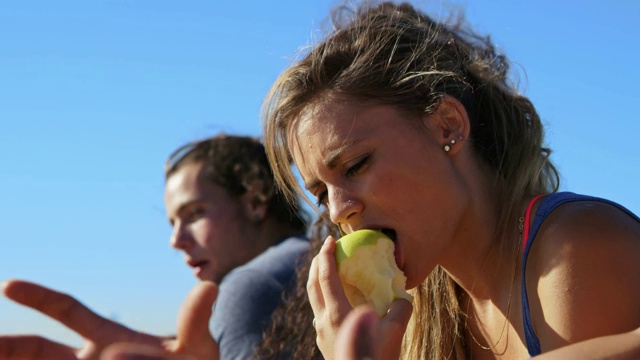 女运动员在海滩上和朋友们吃苹果视频下载
