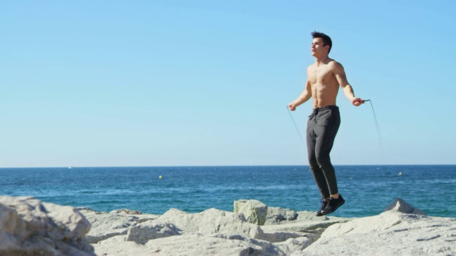 活跃的赤膊运动员在海滩上跳绳视频下载