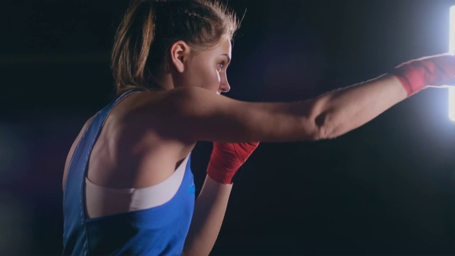 女子拳击训练在暗室与背光慢动作侧视图。替身拍摄视频下载