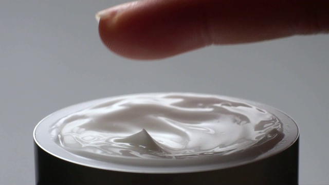 慢动作:特写的手触摸霜保湿产品。视频下载