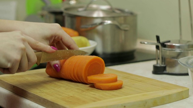 一位家庭主妇在厨房里用手把胡萝卜切成小块视频素材