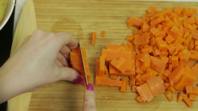 一位家庭主妇在厨房里用手把胡萝卜切成小块视频素材
