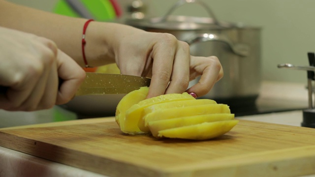 一位家庭主妇在厨房里用手把土豆切成片视频素材
