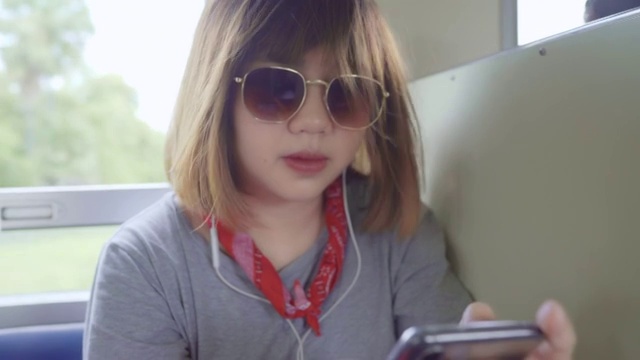 亚洲女性乘火车时用智能手机听音乐放松。视频素材