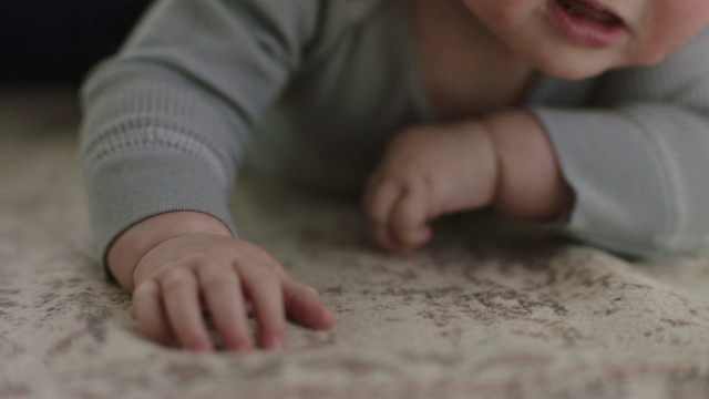 ECU SLO MO，可爱的宝宝用手伸到客厅的地毯上。视频素材