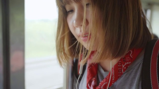 亚洲女性乘火车时用智能手机听音乐放松。视频素材