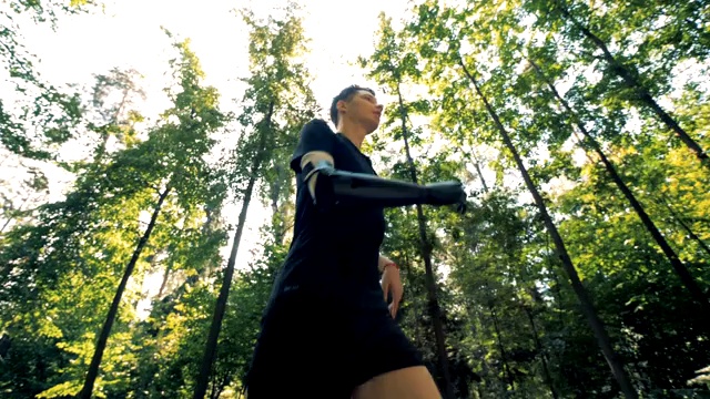 一个年轻的机械人戴着他的特殊的假肢在森林里慢跑。4 k。视频下载
